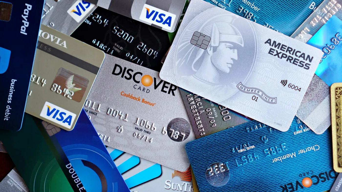 A close-up pile of credit cards from the major networks, representing the card networks and processors that came together behind a single standard for how AI agents pay.