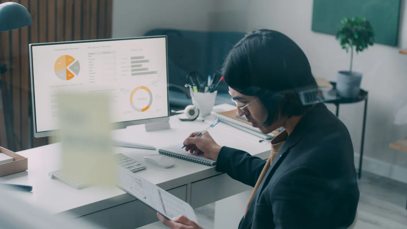 A person at a desk studying charts and rankings on a monitor while making notes, the new routine of checking where a business lands on a public readiness score.