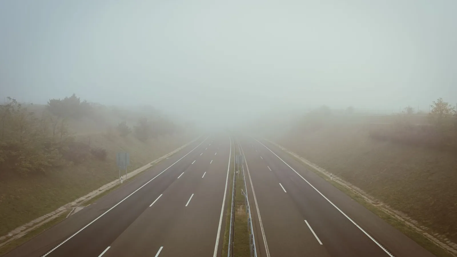An empty highway swallowed by fog.