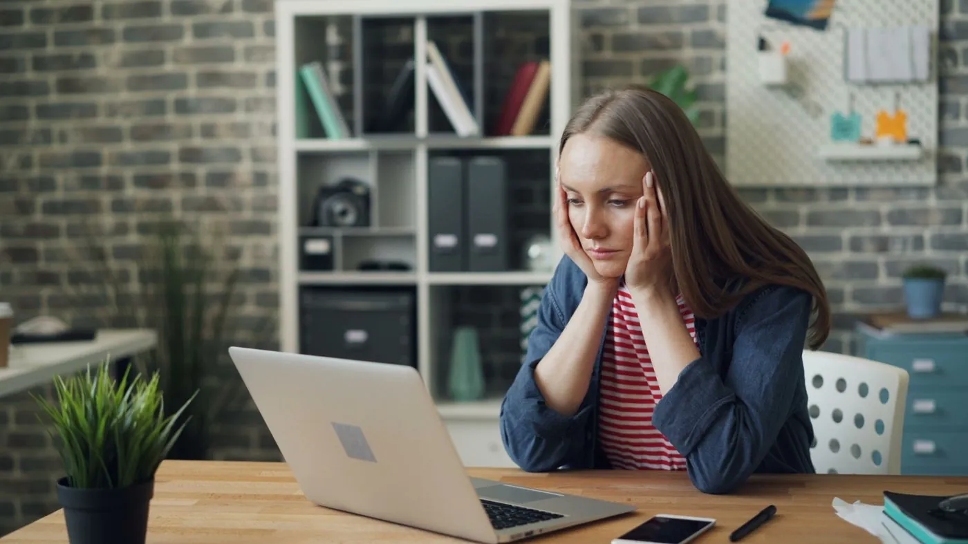 A worried business owner looking at a laptop screen in an office.